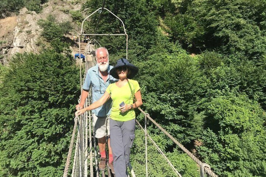 Een stel loopt over een hangbrug, omringd door weelderige begroeiing. 4