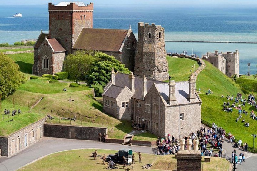 A historic castle with a tower, surrounded by a grassy area and a body of water. 2