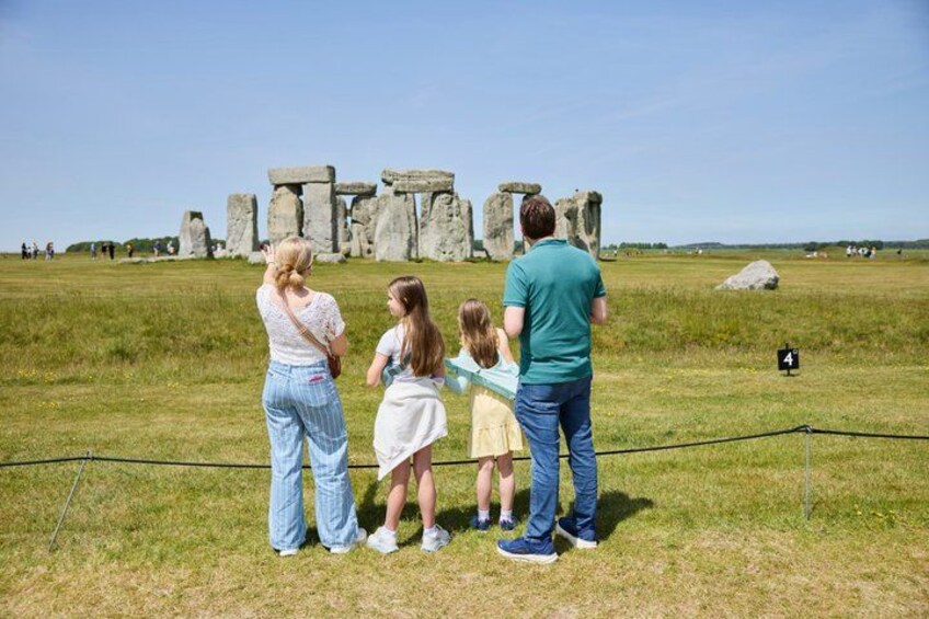 Una familia parada frente a Stonehenge, con una vista despejada del antiguo círculo de piedras. 4
