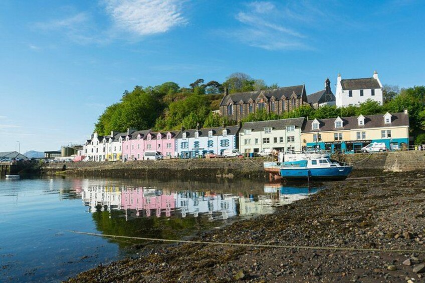 A coastal town with colorful buildings, a calm river, and a small boat docked at the shore. 4