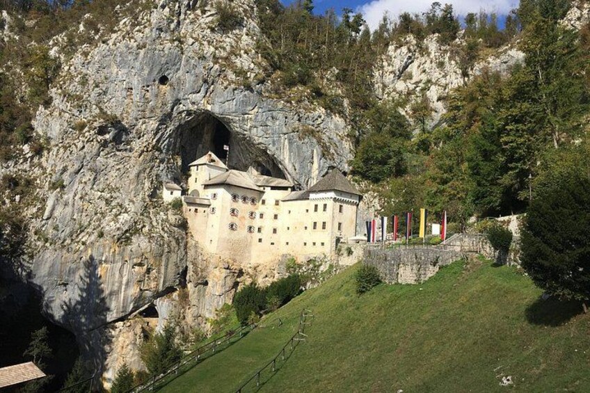 Un castello integrato in una scogliera, circondato da vegetazione e bandiere. 3