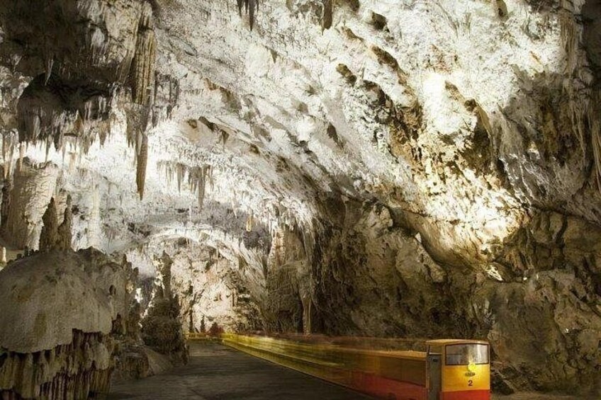 Un treno che viaggia attraverso una grotta con stalattiti e stalagmiti. 5