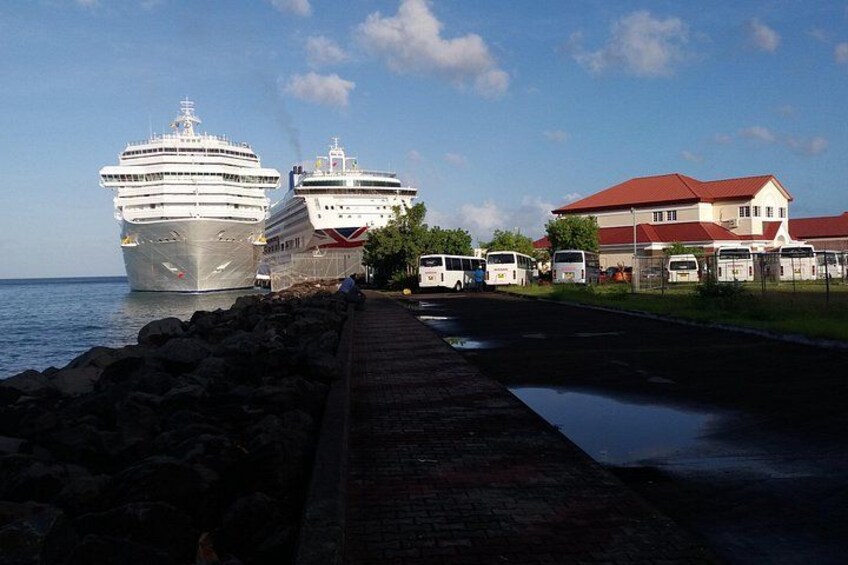 A cruise ship docked at a port, a pier with buses, and a building with a red roof. 4