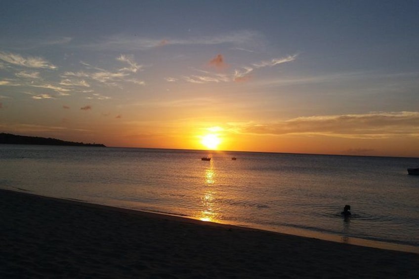 A sunset over a calm sea with a beach in the foreground. 2