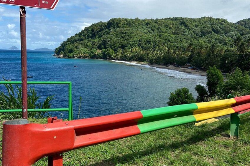 A coastal landscape with a beach, a forested hill, and a signpost. 3