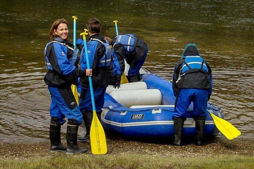 Un grupo de personas con chalecos salvavidas azules preparando un bote inflable azul en aguas tranquilas. 2
