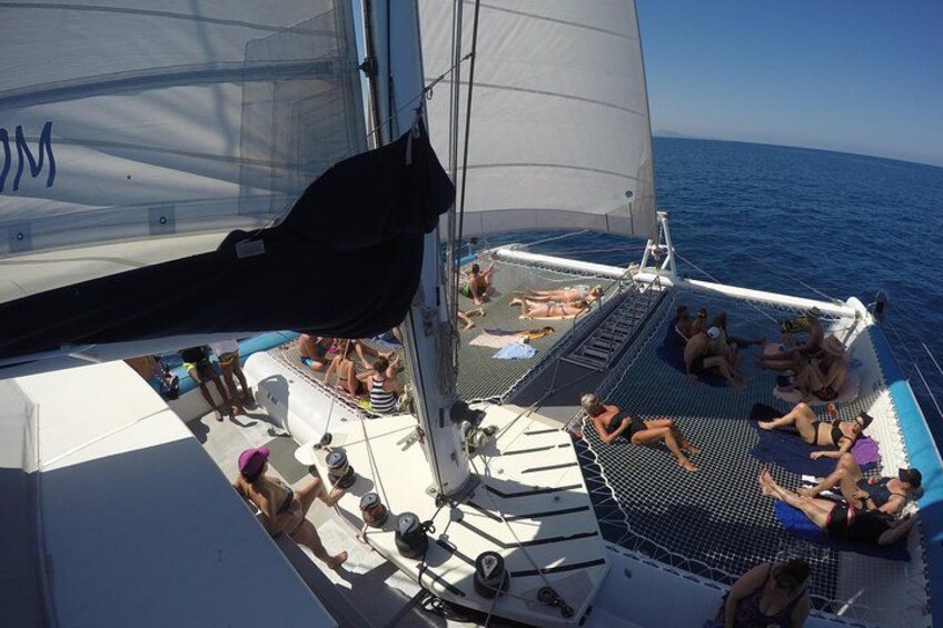 Een zeilboot met mensen die ontspannen in deckstoelen en liggen zonnebaden op het zonnedek. 3