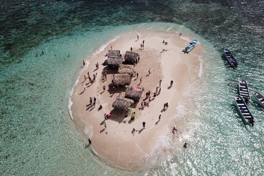 An aerial view of a beach with people, thatched huts, and boats. 5