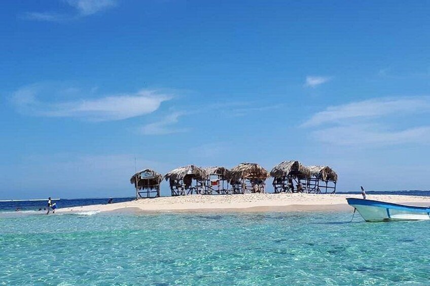 Una playa con chozas de techo de paja y un bote en la orilla. 4