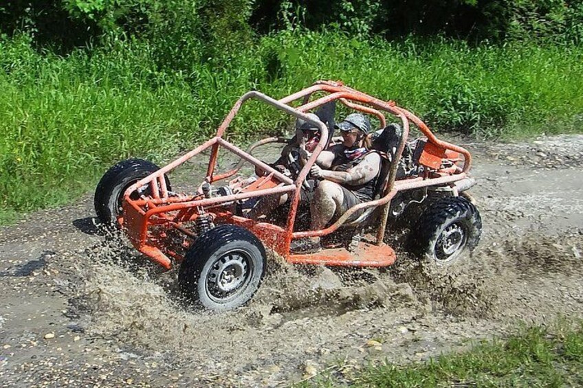 A red off-road vehicle driving through a muddy path. 4