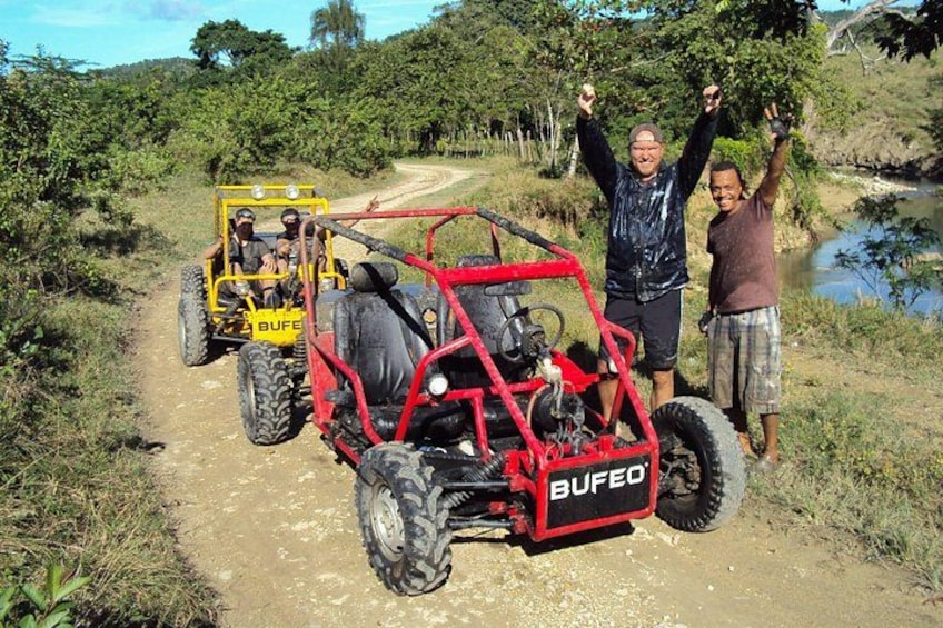Two off-road vehicles on a dirt path with people standing beside them. 3