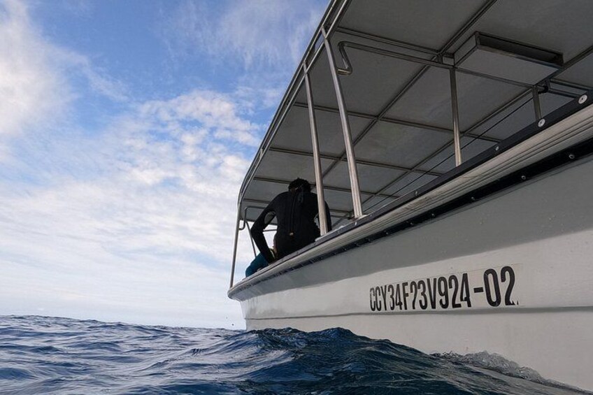 A boat with a person on deck, water, and a partly cloudy sky. 2