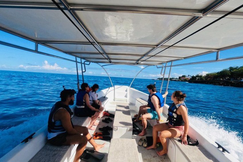 Ein Boot mit Passagieren, Wasser und einer Küstenlinie im Hintergrund. 1