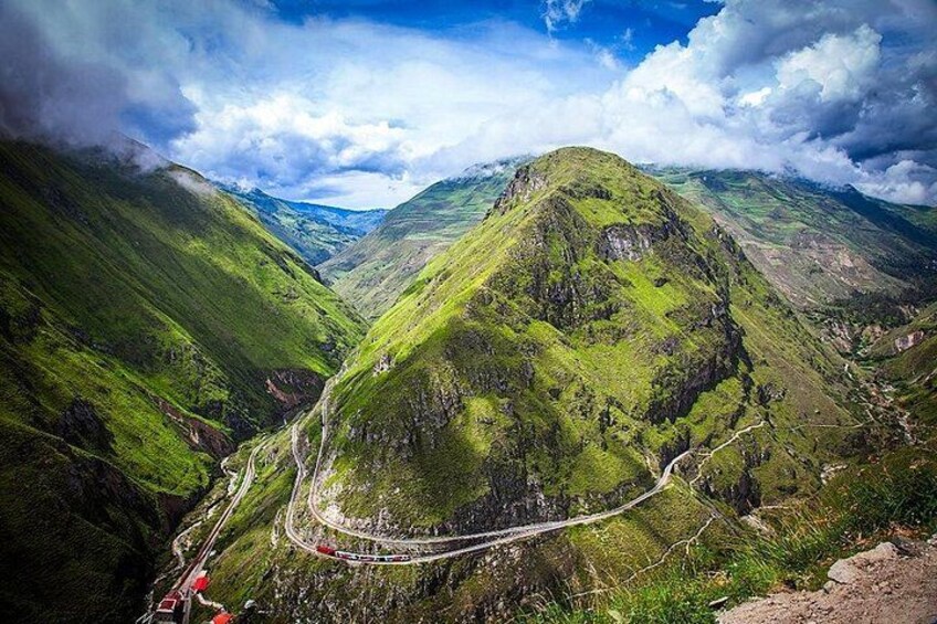 Un paisaje montañoso con un camino sinuoso, colinas verdes exuberantes y un valle. 1