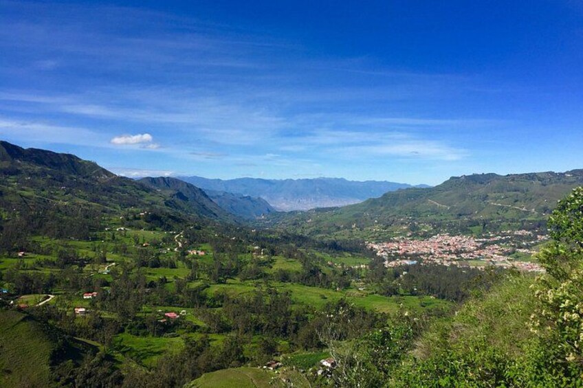 Paisaje montañoso con un valle, un pueblo y cielo azul despejado. 4