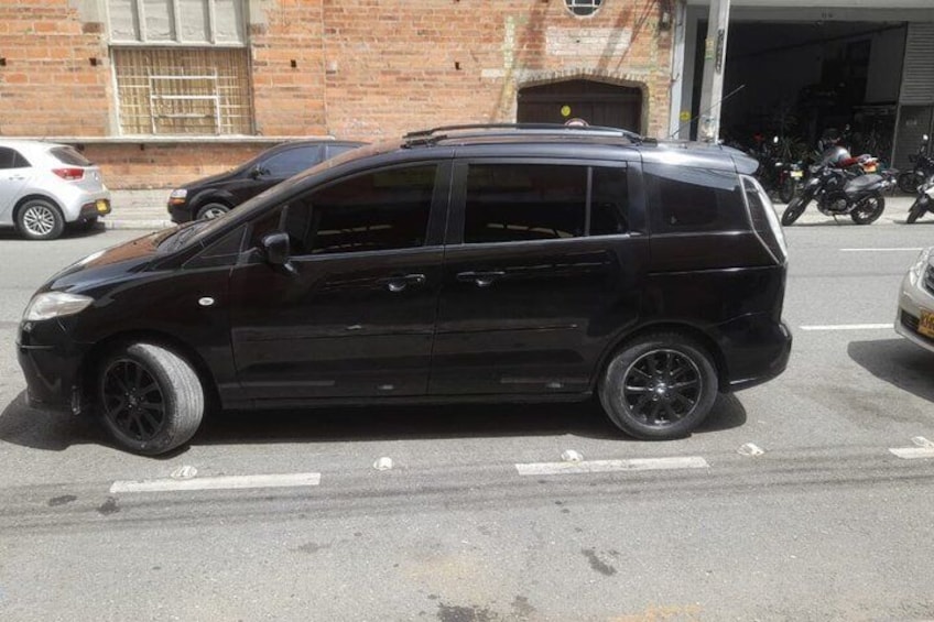 Un coche negro estacionado en una calle con un edificio de ladrillo y una motocicleta al fondo. 3