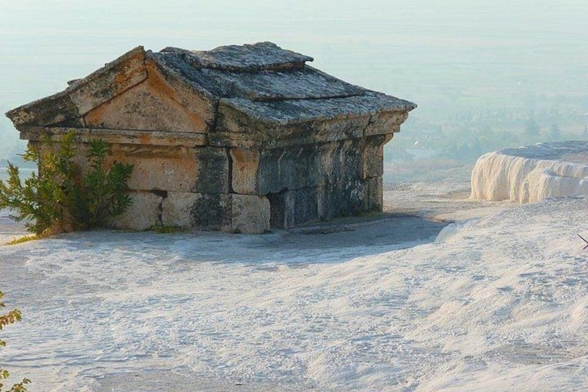 A stone structure with a triangular roof, surrounded by a snowy landscape and distant mountains. 2