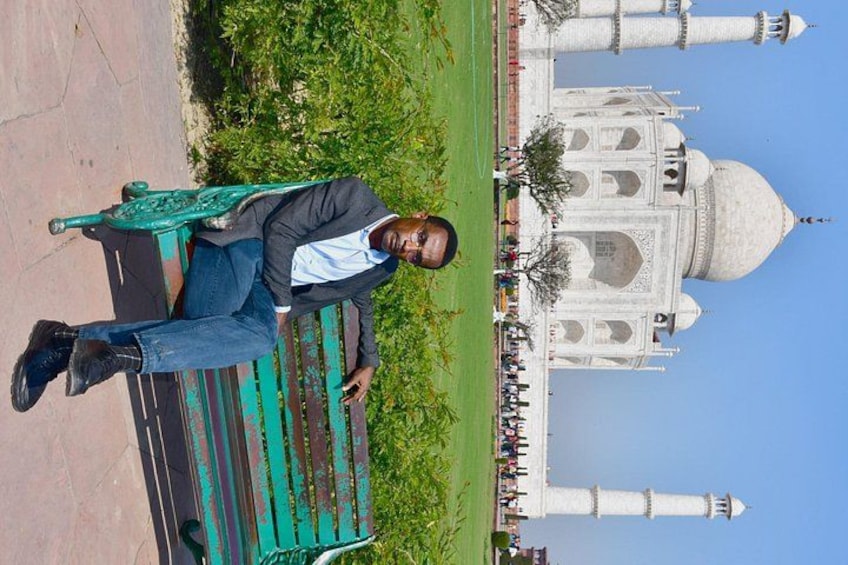 Eine Person sitzt auf einer Bank, im Hintergrund der Taj Mahal. 5