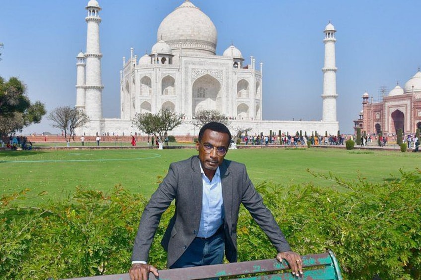 Eine Person im Anzug vor dem Taj Mahal, mit Minaretten und Kuppel im Hintergrund. 3