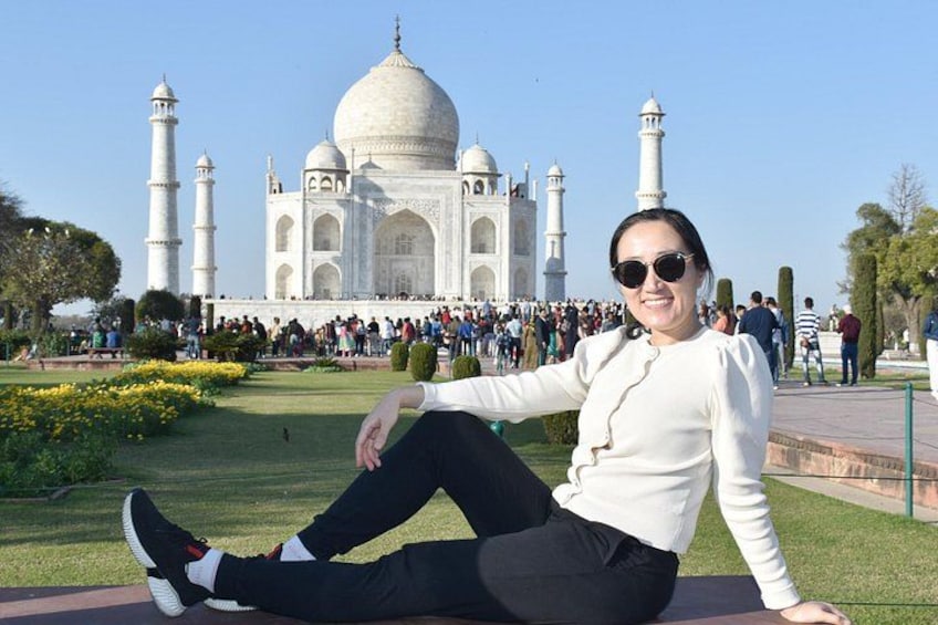 Eine Person sitzt auf einer Bank, im Hintergrund das Taj Mahal. 1