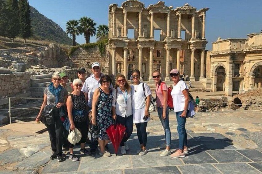 A group of people standing in front of ancient ruins with columns and steps. 1