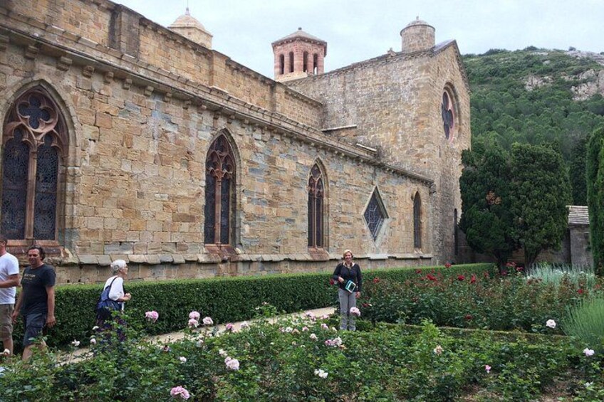 Ein historisches Steinhaus mit Bogenfenstern und einem Garten mit rosa Blumen. 3