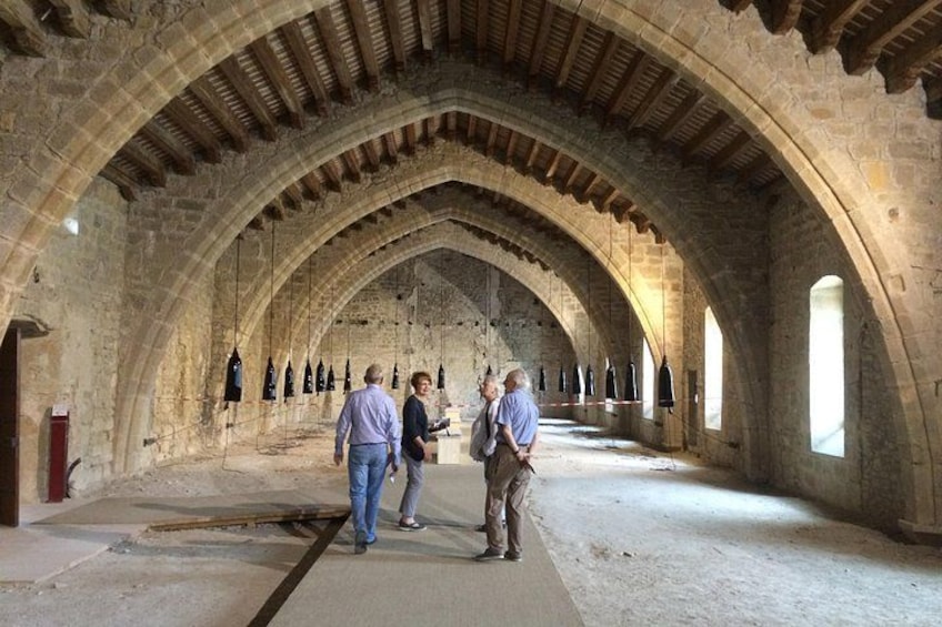 Een interieur met gewelfde plafonds en stenen muren, met een centrale doorgang en hangende objecten. 5