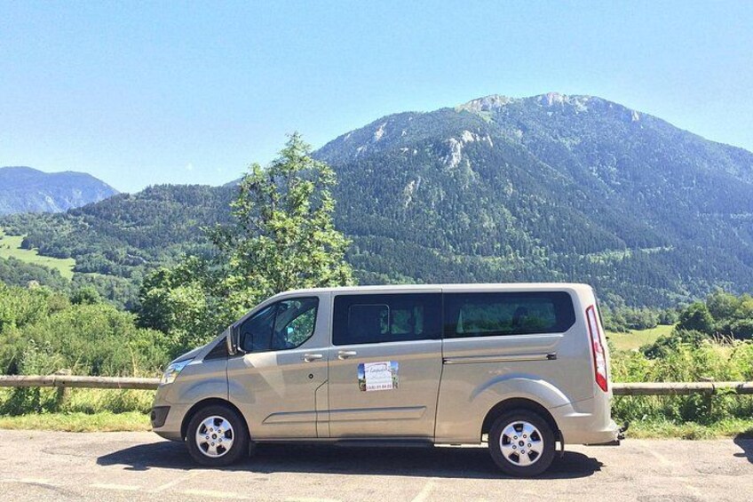 A beige minivan parked on a road with a mountainous landscape in the background. 5