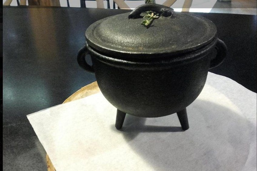 A black cast iron pot with a lid on a white paper towel on a table. 2