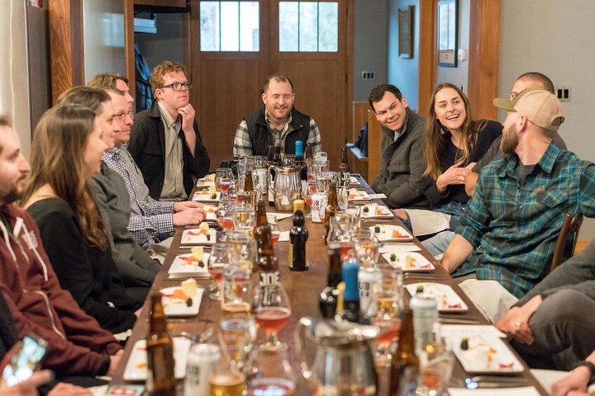 A group of people seated around a long table with food and drinks. 2