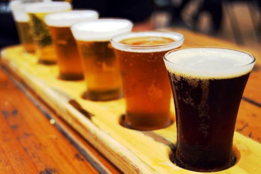 A series of beer glasses lined up on a wooden surface. 5