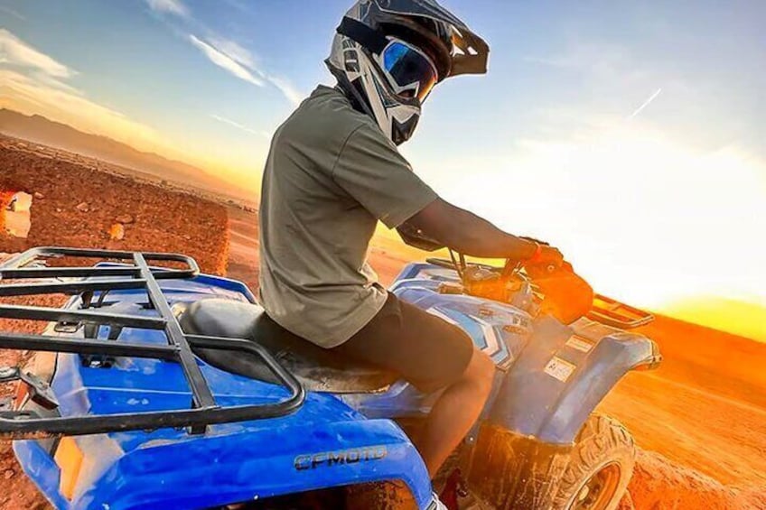A person riding a blue ATV in a desert landscape during sunset. 2