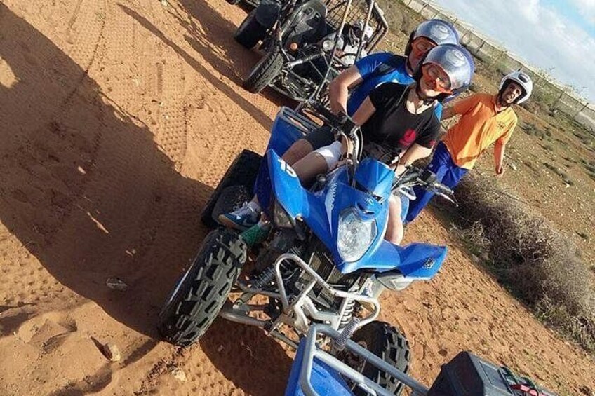 Una motocicleta azul sobre terreno arenoso, con una persona usando casco. 2