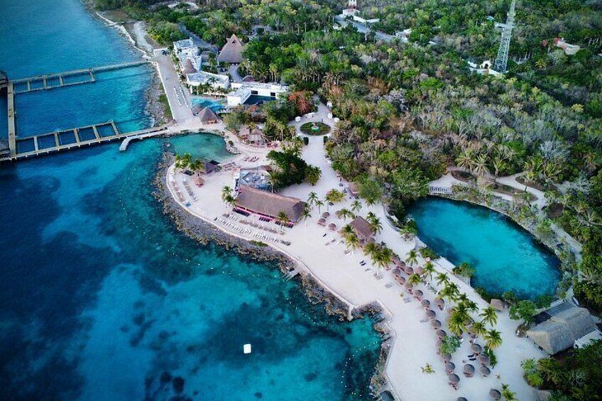 Una vista aerea di un resort costiero con spiaggia, acque blu cristalline e vegetazione lussureggiante. 1