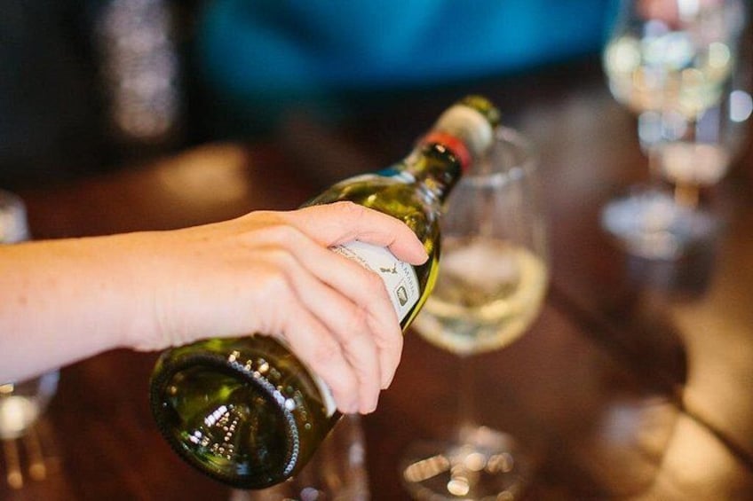 A hand holding a wine bottle, pouring wine into a glass. 2