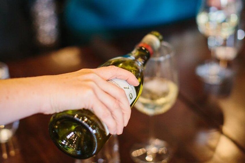 Eine Hand hält eine Weinflasche und gießt Wein in ein Glas. 2