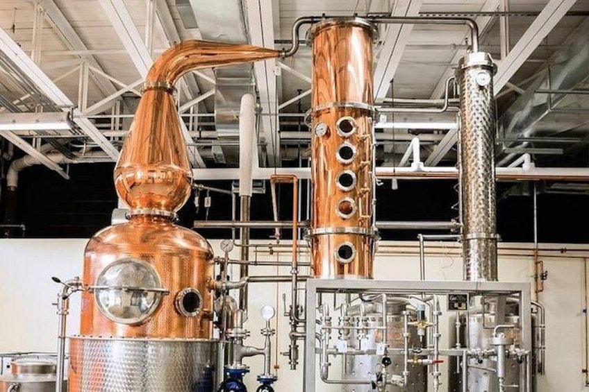 Un appareil de distillation en cuivre, doté de plusieurs colonnes et de tuyaux, installé dans un environnement industriel. 3