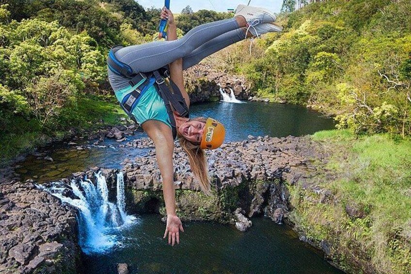 A person performing a handstand over a waterfall in a natural setting. 2