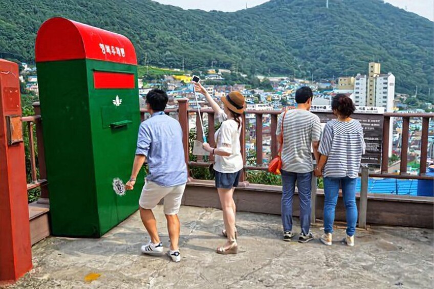 A group of people standing on a bridge overlooking a city and a mountain. 2