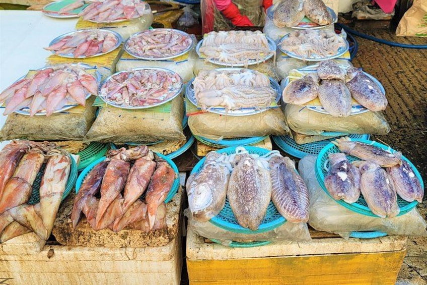 A variety of fresh fish displayed on trays and in baskets at a market. 3