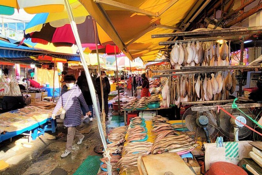 A market with fish displayed on racks and tables, under colorful umbrellas. 2