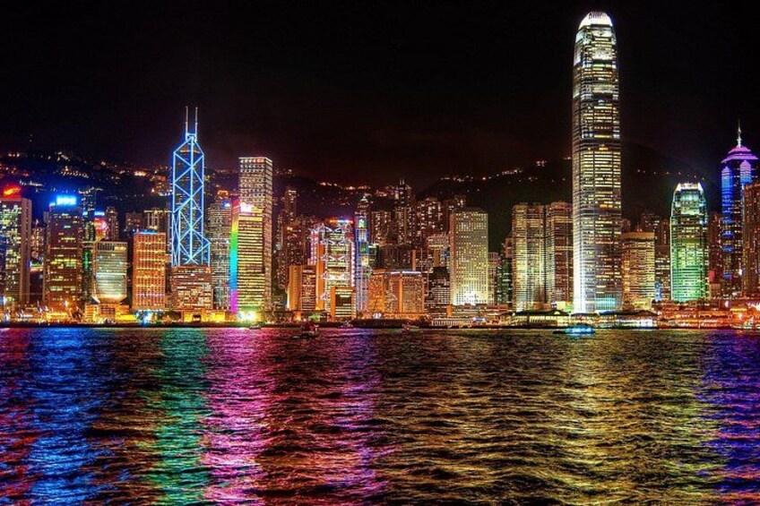 A nighttime cityscape with illuminated skyscrapers reflecting on the water. 1