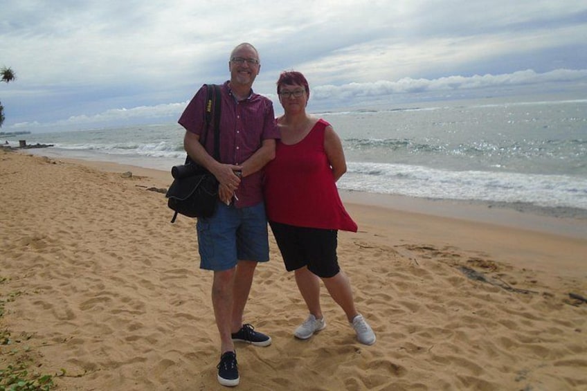 Two people standing on a sandy beach with the ocean in the background. 4