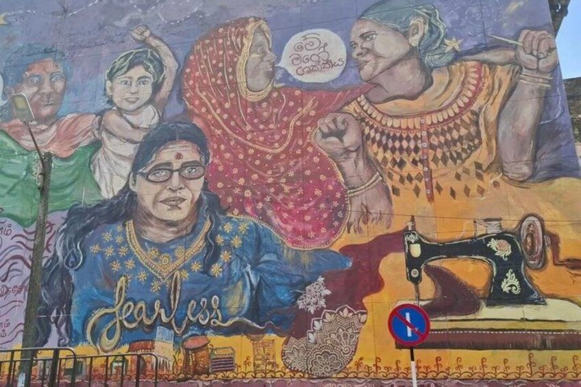 A mural with people in traditional attire, a sewing machine, and the word 'fearless' on a blue garment. 3