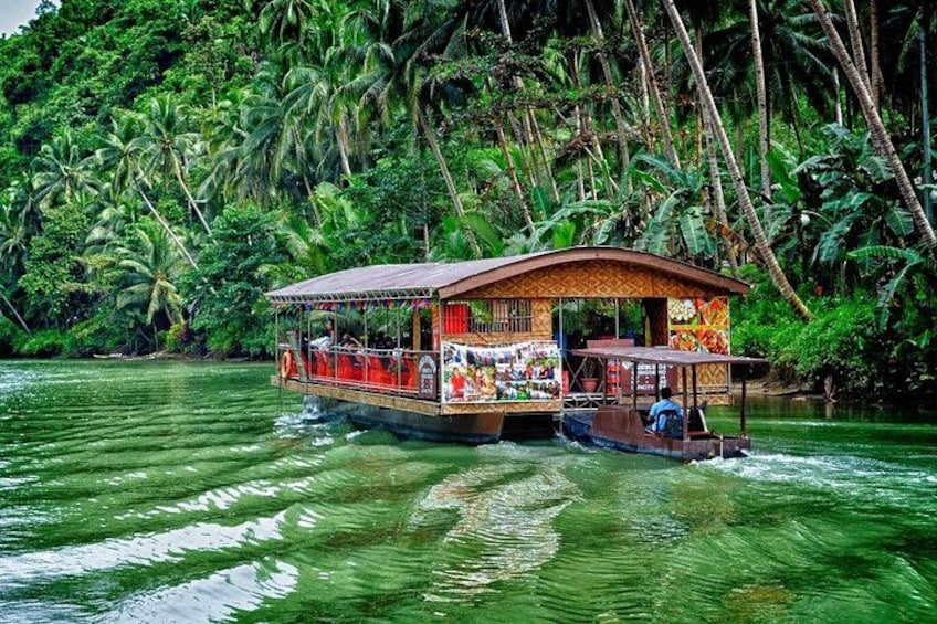 A houseboat with a covered deck and a person seated at the front. 4