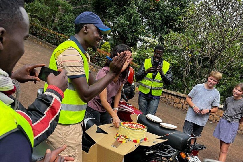 A group of people around a table with a cake and a motorcycle. 3