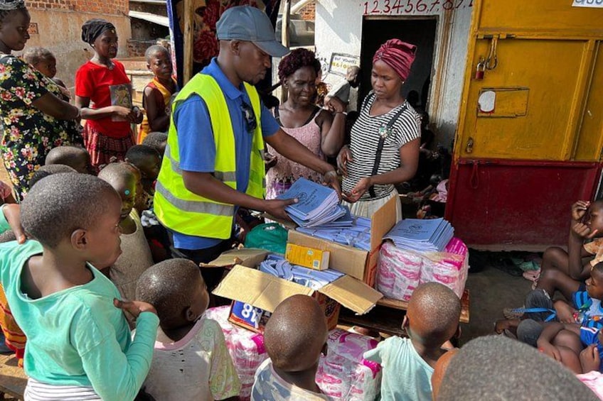 A group of people, including children, gathered around a table with boxes and papers, possibly at a community event or distribution center. 5