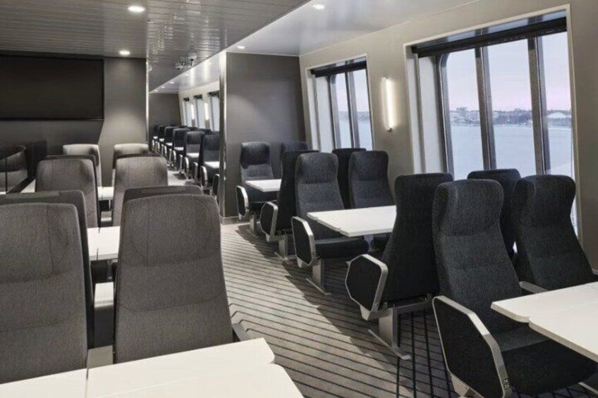 A ship's dining area with rows of tables and chairs, large windows, and a view of the water. 3