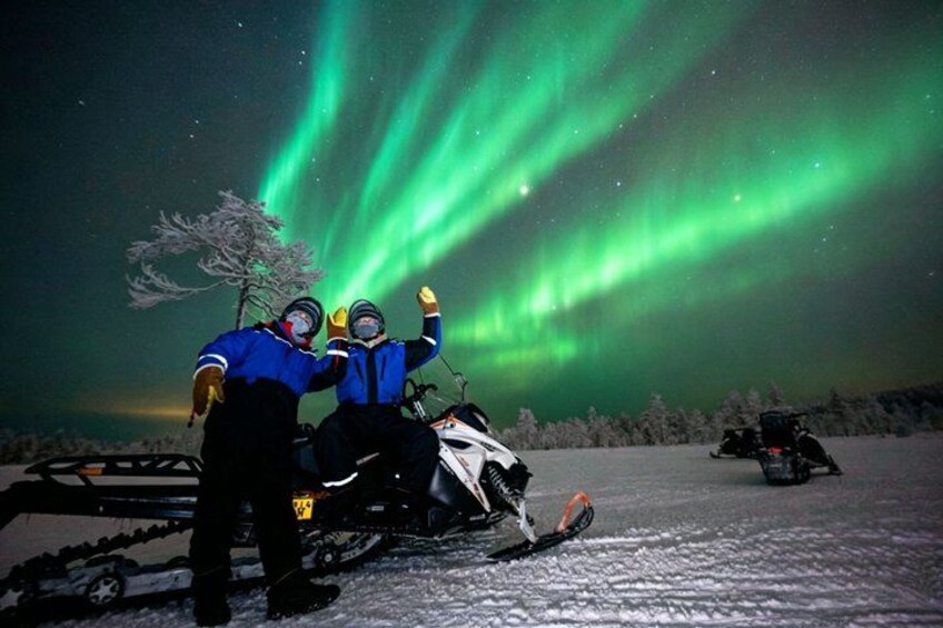 Dos personas en un vehículo de nieve, un paisaje nevado y las auroras boreales. 5