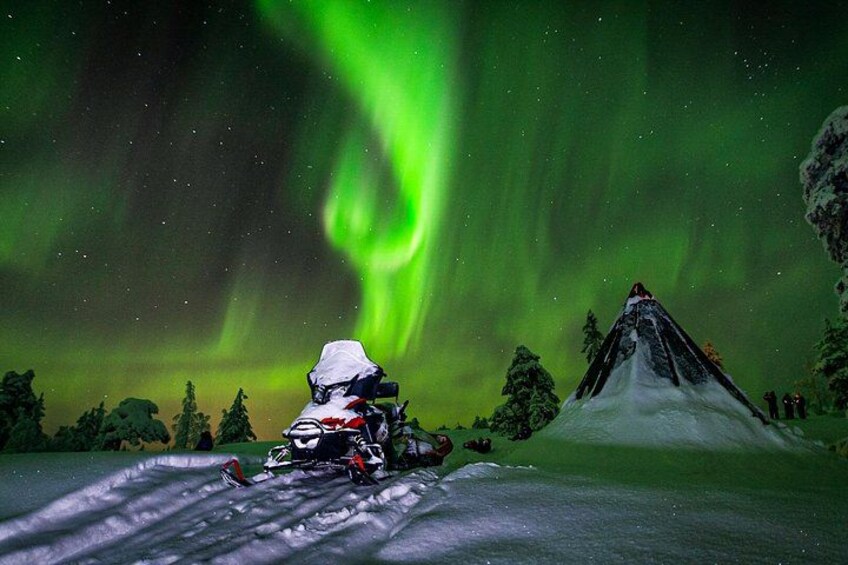 Un vehículo de nieve en un paisaje nevado con una montaña y una aurora verde en el fondo. 1